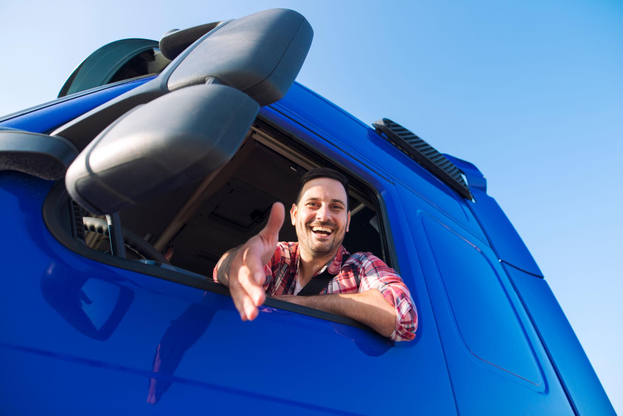 Professional extending a hand in greeting beside a commercial vehicle, representing partnership and trust.